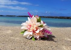 a bouquet of flowers sitting on top of a sandy beach