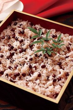 rice and beans are served in a square dish with a sprig of rosemary