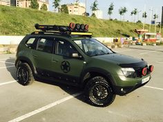 a green vehicle with some lights on it's roof rack in a parking lot