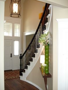 an entryway with stairs and a vase on the floor