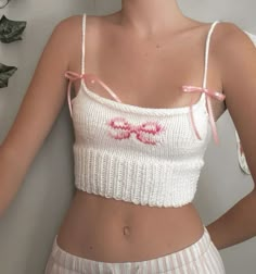 a woman wearing a white crop top with pink bows