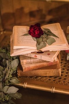 an open book with a rose on top of it sitting on a table next to some flowers