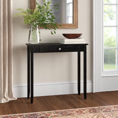 a small table with a mirror and vase on it in front of a door way