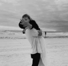 a man carrying a woman on his back while standing in the sand at the beach