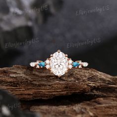 an oval cut diamond ring with blue stones in the center on top of a piece of wood