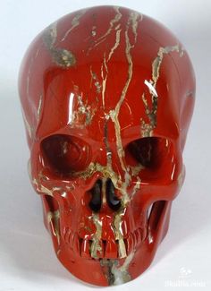 a red and gold skull is shown on a white background with cracks in the surface