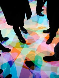 several people standing in the middle of a multicolored floor with their feet up