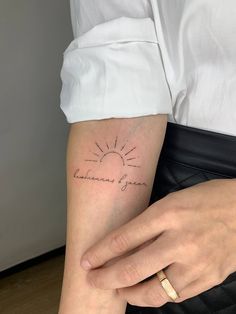 a woman with a small sun tattoo on her arm that reads, i love you