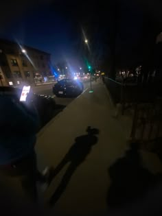 a blurry image of a person walking down the street at night with their shadow on the sidewalk