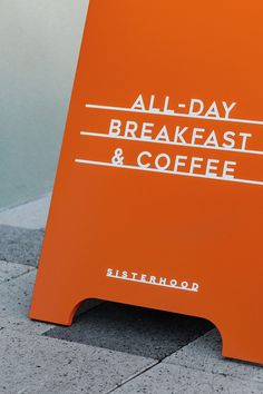 an orange sign that says all day breakfast and coffee