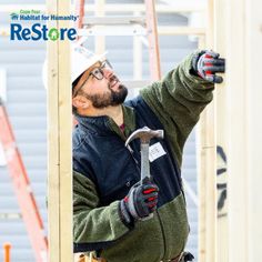 a man holding a hammer in his right hand while standing next to some scaffolding