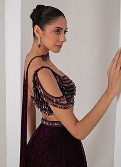 This stunning Black Platinoir Crepe Embellished Lehenga Set exudes modern elegance and glamour. Crafted from luxurious platinoir crepe, the black lehenga features a dramatic full-length skirt with all-over metallic brazen fall detailing, adding a shimmering effect with every movement. The crystal-embroidered waistband accentuates the waist, offering a refined silhouette. Teamed with a cold shoulder blouse, the ensemble reaches new heights with its halo crystal tassel embellishments, delivering a unique and stylish twist. The look is completed with a choker-style embellished dupatta, perfectly complementing the outfit with a sophisticated touch. Ideal for Cocktail parties, Sangeet nights, or evening events, this lehenga set is designed for those who wish to make a bold and fashionable state Embellished Lehenga, Black Lehenga, Full Length Skirts, Embroidered Lehenga, Cold Shoulder Blouse, Choker Style, Cocktail Parties, Wedding Wear, Modern Elegance