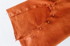 an orange piece of cloth with holes in the middle and some thread on it that has been stitched together