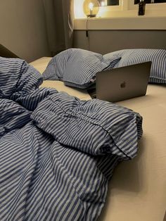 an apple laptop computer sitting on top of a bed covered in blue and white sheets