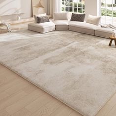 a living room with a large white rug on the floor and windows in the background