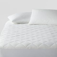 an unmade bed with white sheets and pillows