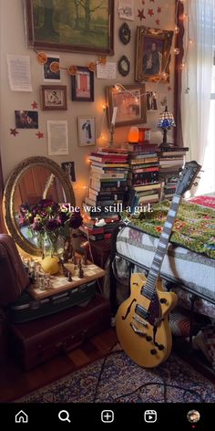 a guitar sitting on top of a bed next to a dresser and window with pictures above it