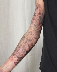 a man's arm with a cross and flowers tattoo on his left arm, in front of a white background