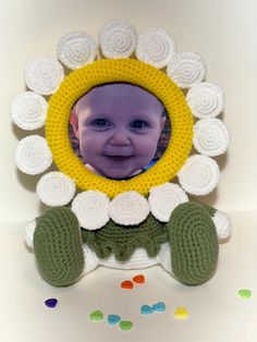 a crocheted photo frame with a smiling baby's face in the center