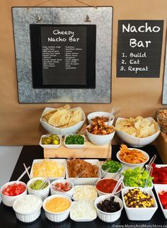 an assortment of food is displayed on a buffet table with chalkboard menus in the background