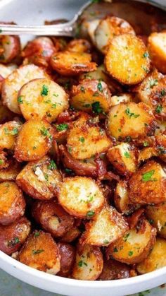 a white bowl filled with cooked potatoes and parsley