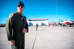 a man in an air force pilot's uniform standing on the tarmac