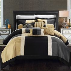 a bed with black and yellow comforters in a bedroom next to a night stand