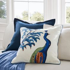 the pillows on the couch are decorated with blue and green designs, including a peacock