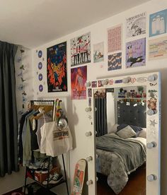 a bedroom with a bed, mirror and various posters on the wall