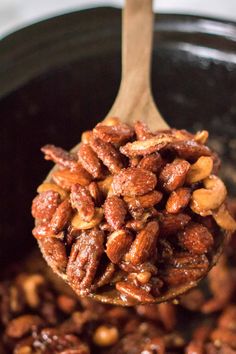 a wooden spoon filled with nuts on top of a pot full of other nuts in it