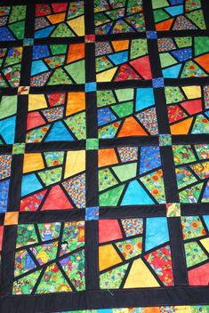 a colorful quilt with many different colored squares on the top and bottom, as well as black background