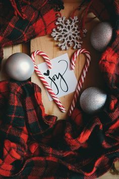 an ornament, candy canes and ornaments on a wooden board with the word joy