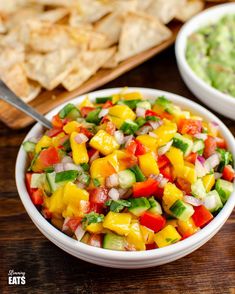 two bowls filled with colorful fruit and veggies next to tortilla chips