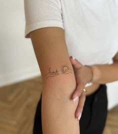 a woman with a tattoo on her arm holding onto another person's arm, both arms behind her back