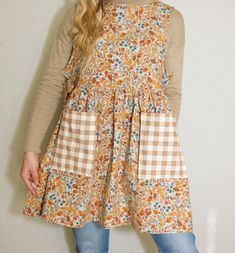 a woman standing in front of a white wall wearing a brown and blue floral dress