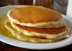 two pancakes are stacked on top of each other in a white plate with syrup and butter