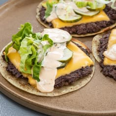 three hamburgers with cheese and lettuce on them are sitting on a plate