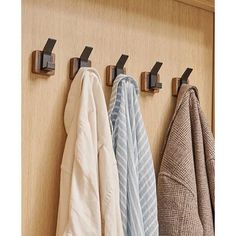 three towels are hanging on the hooks in this bathroom cabinet door handle system, which also holds several folded towels