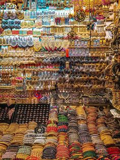 many bracelets and necklaces are on display in a market stall with lots of them