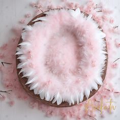 a cake with white feathers and pink flowers on it's top, surrounded by petals