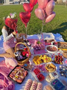 a table topped with lots of food and balloons in the shape of heart shaped balloons