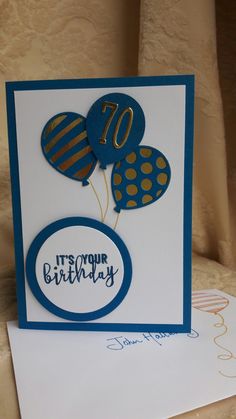 a birthday card with balloons and the number seventy on it's front, sitting on a table