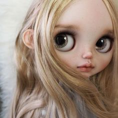 a doll with long blonde hair and big brown eyes is posing for the camera,