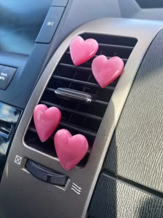 three pink hearts are attached to the air vent in a car