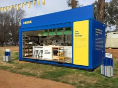 a blue and yellow container sitting on top of a grass covered field next to trees