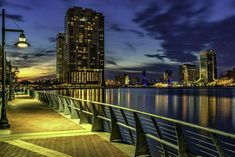 the city skyline is lit up at night, along with its lights reflecting in the water