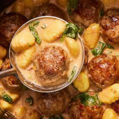 a pan filled with meatballs and potatoes covered in gravy next to a spoon