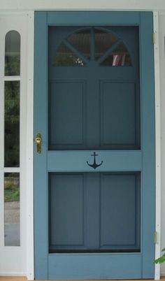 a blue front door with an anchor on it and flowers in the window box below