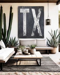 a living room filled with lots of plants next to a large painting on the wall