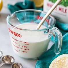 a measuring cup filled with white liquid next to lemons